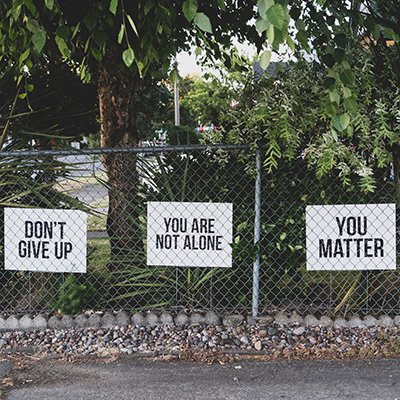Three signs on a chain-link fence that read, "Don't Give Up", "You Are Not Alone", and "You Matter"