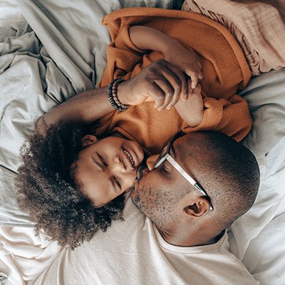 Father kissing his son on the cheek, while laying in bed
